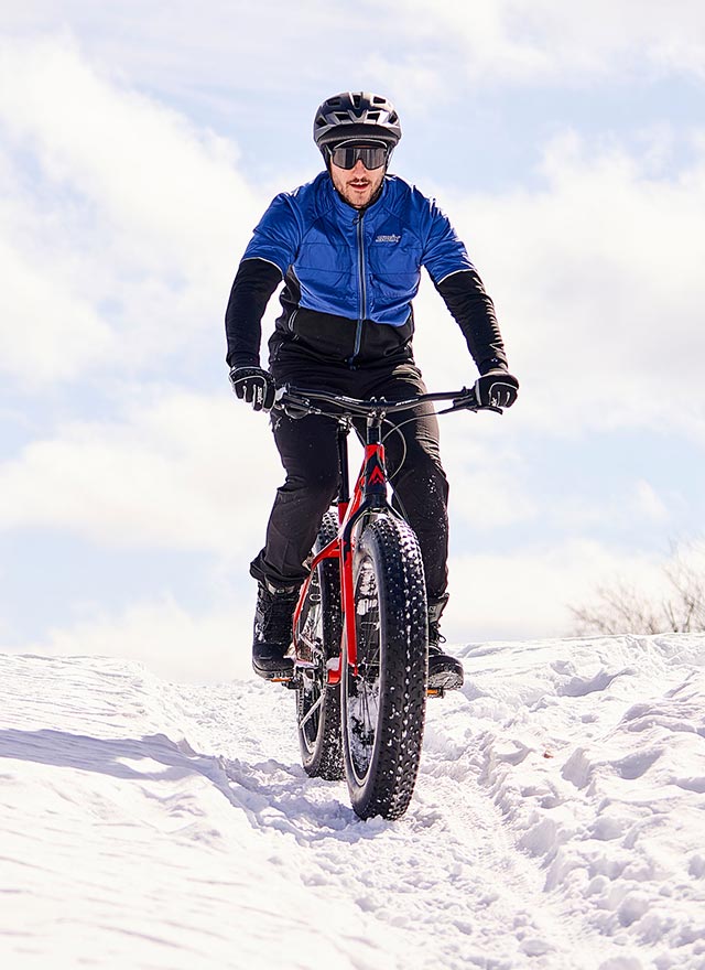 Homme qui fait du fatbike sur une piste enneigée