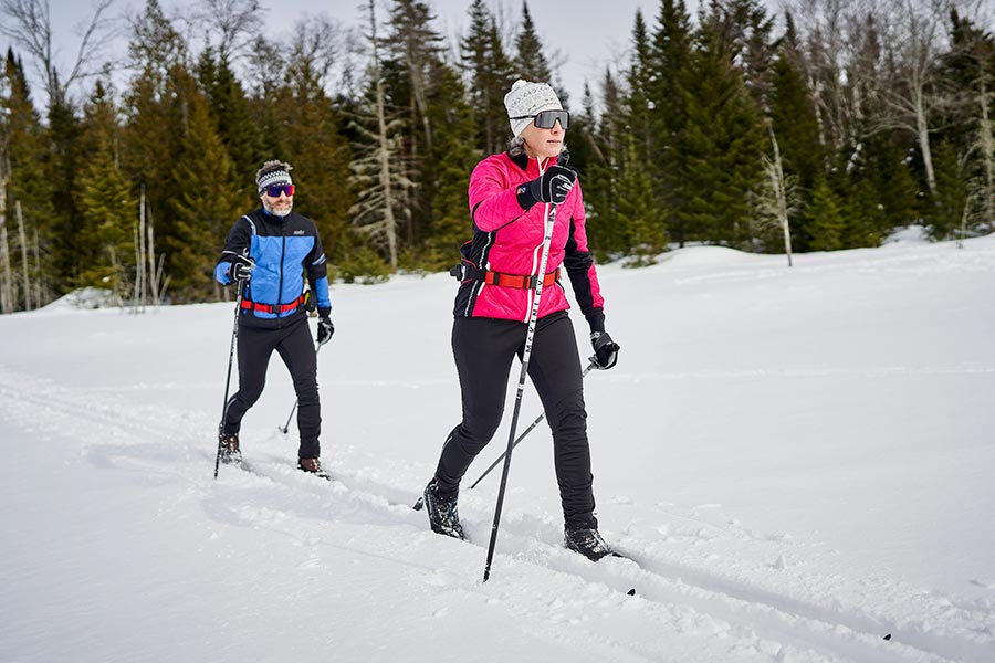 Femme et homme qui pratiquent du ski de fond dans un sentier