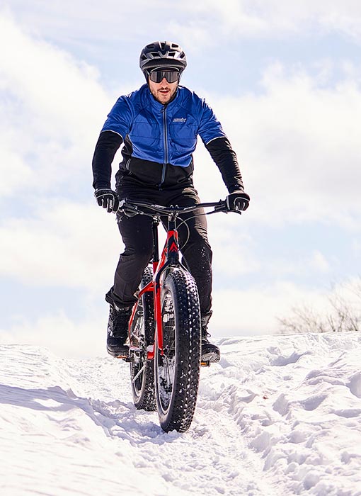 Homme qui fait du fatbike sur une piste enneigée